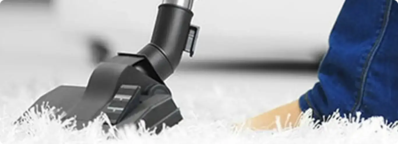 Close-up of a professional vacuuming a white carpet in Riverside.
