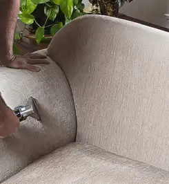 Professional upholstery cleaner deep-cleaning a fabric sofa with a handheld extraction tool and hose Chicago, IL.